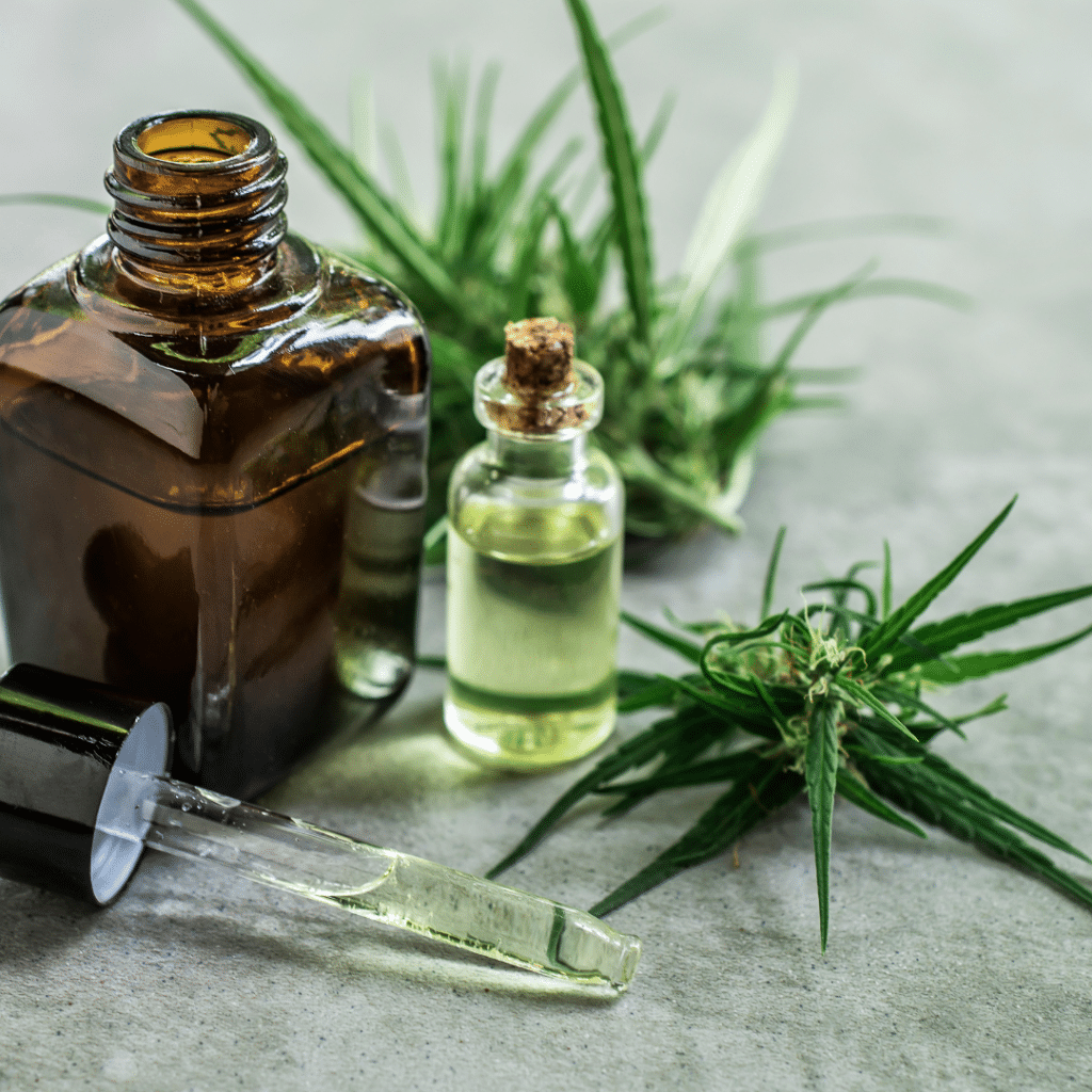 brown bottle with a dropper and a smaller bottle with liquid in it surrounded by greenery
